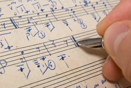 Hand with pen and music sheet - musical background